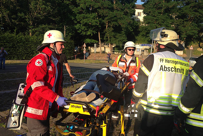 Sanitäter mit einem Verletzten siwie dem Abschnittsleiter der Feuerwehr.